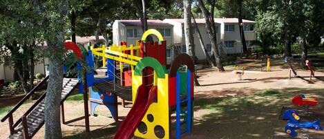Un parque infantil con diversas estructuras de juego, como toboganes, escaleras de cuerda y columpios.
