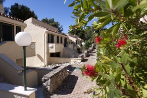 A row of traditional Mediterranean-style buildings with stone walls and tiled roofs, a narrow paved pathway, and a street lamp. - Apartments Bellevue Plava Laguna (Porec)