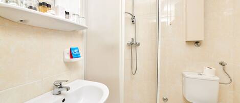 Une salle de bain avec un lavabo blanc, une cabine de douche en verre et des toilettes.
