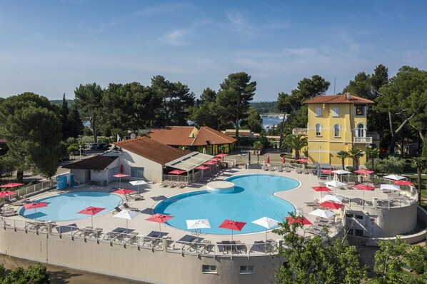 A resort with a large swimming pool, sun loungers, and umbrellas. - Apartments Bellevue Plava Laguna (Porec)