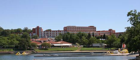 A large hotel with multiple floors and a swimming pool in the foreground.