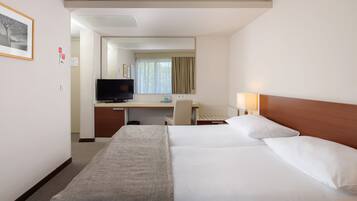 Una habitación de hotel con cama, escritorio, televisor y espejo.