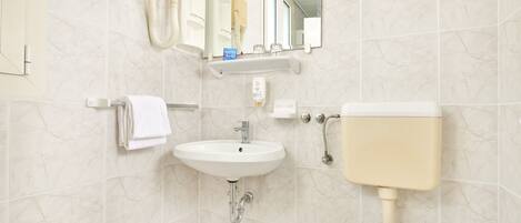 A bathroom with a white sink, toilet, and a mirror above the sink.