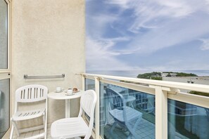 A balcony with two white chairs and a small table, overlooking a cityscape with buildings and a distant view of the sea. - Hotel Gran Vista Plava Laguna (Porec)