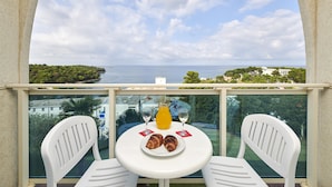 A balcony with a table set for two, a glass of orange juice, and croissants. - Hotel Gran Vista Plava Laguna (Porec)