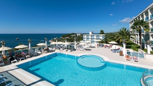 A swimming pool with lounge chairs and umbrellas, a building with balconies, and a view of the sea. - Hotel Gran Vista Plava Laguna (Porec)
