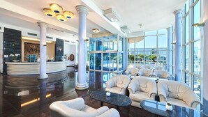 A spacious lobby with a reception desk, seating area, and large windows offering views of the outdoors. - Hotel Gran Vista Plava Laguna (Porec)