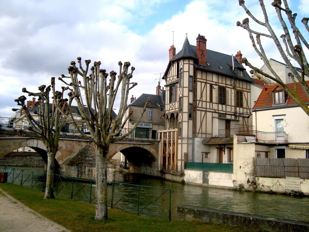 A traditional half-timbered building with a stone bridge and a canal.