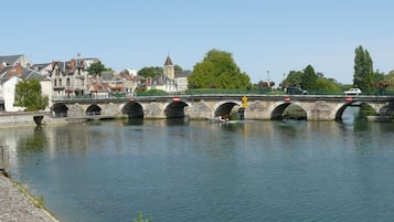 A stone bridge over a river with a town in the background.