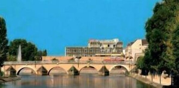 A bridge with multiple arches over a body of water, with buildings on the opposite bank.