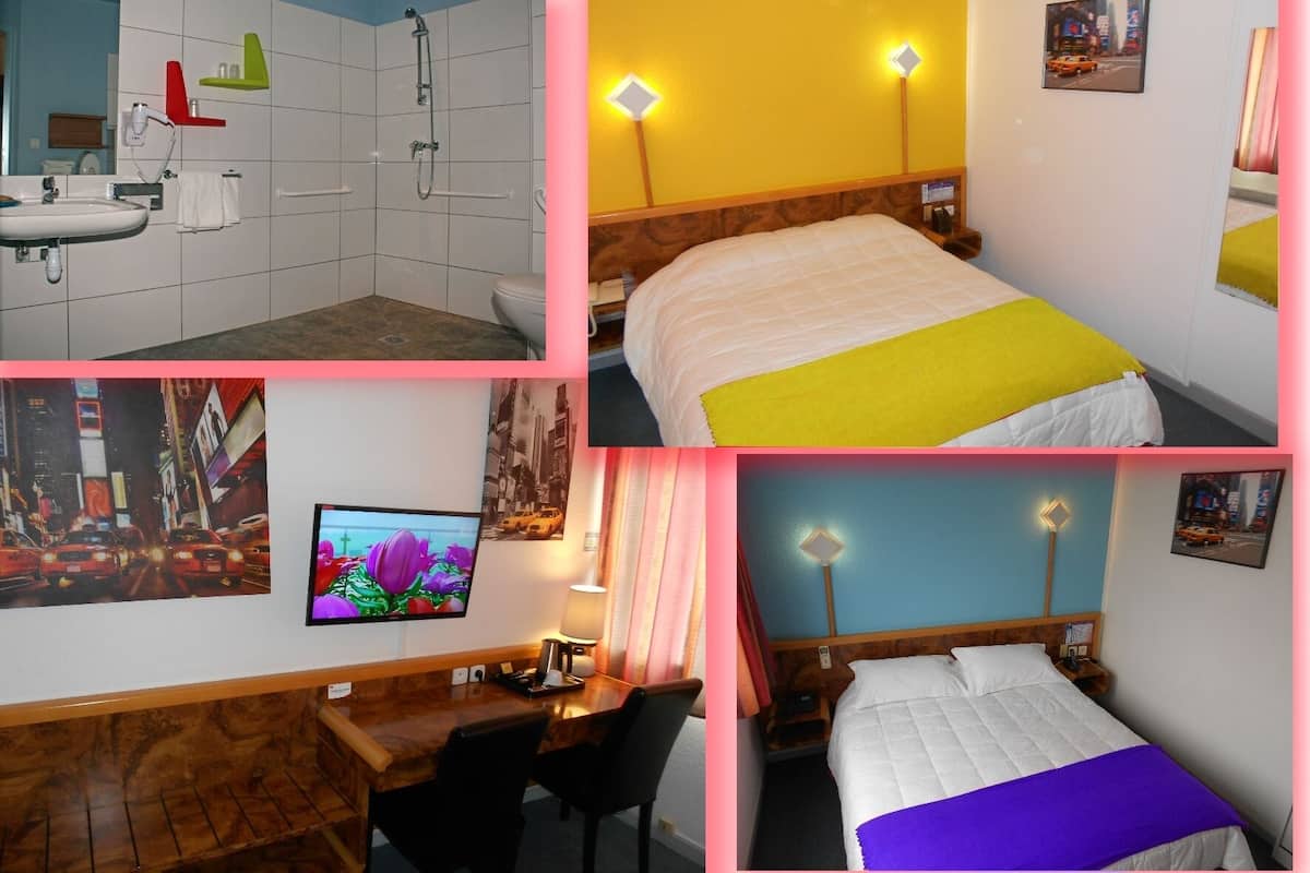 A hotel room with a bathroom, a desk with a chair, a bed with a yellow and white blanket, a TV, and a bed with a purple blanket.
