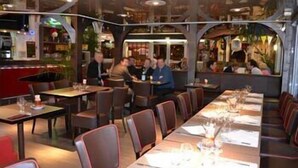 A restaurant with long tables and booths, some occupied by diners. - Arche Hotel (Vierzon)