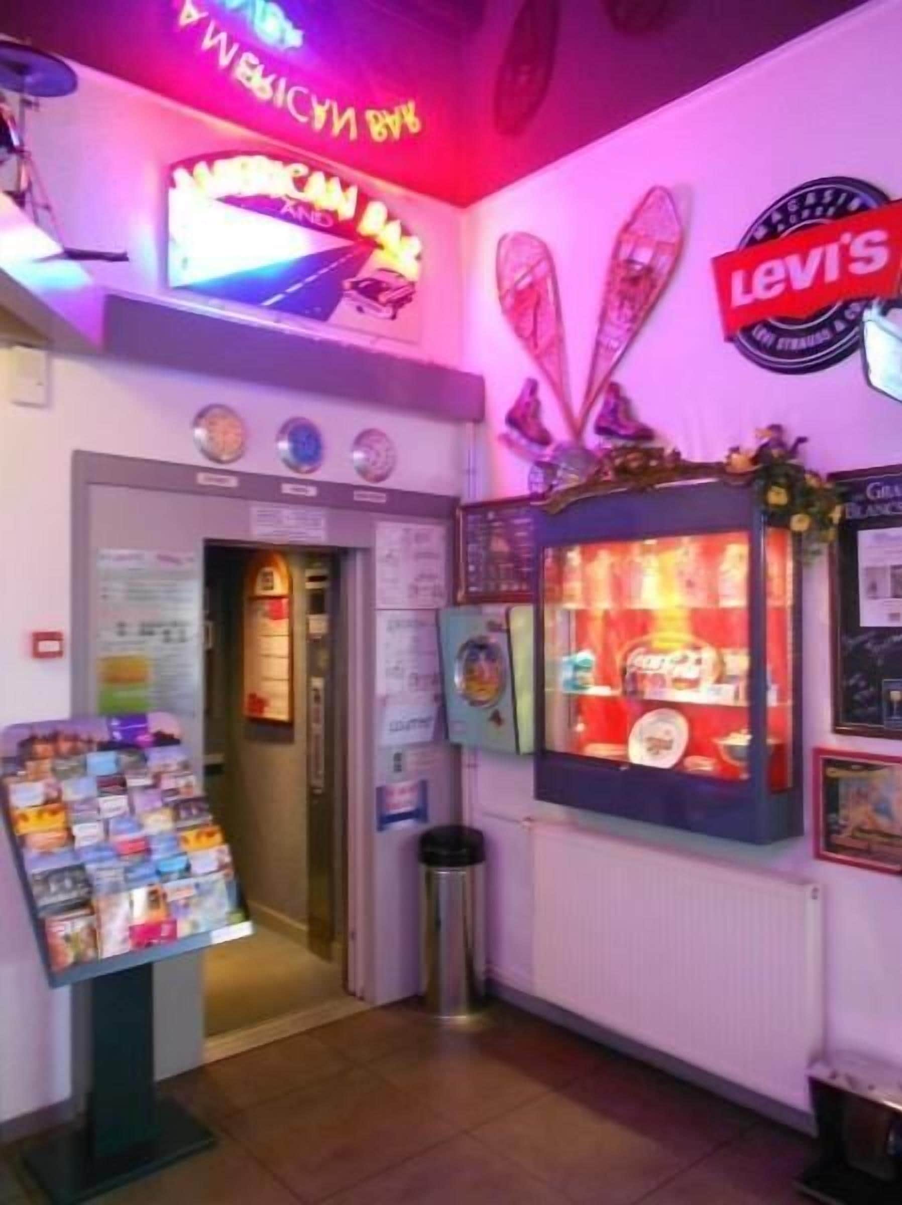 A brightly lit arcade area with neon signs, a vending machine, and a display of magazines.