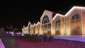 A large, illuminated building with arched windows and a brick facade. - Arche Hotel (Vierzon)