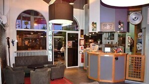 A cozy interior with a reception desk, seating area, and a view of the restaurant. - Arche Hotel (Vierzon)