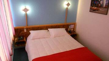 A hotel room with a bed, two bedside lamps, a nightstand, and a wall-mounted picture.