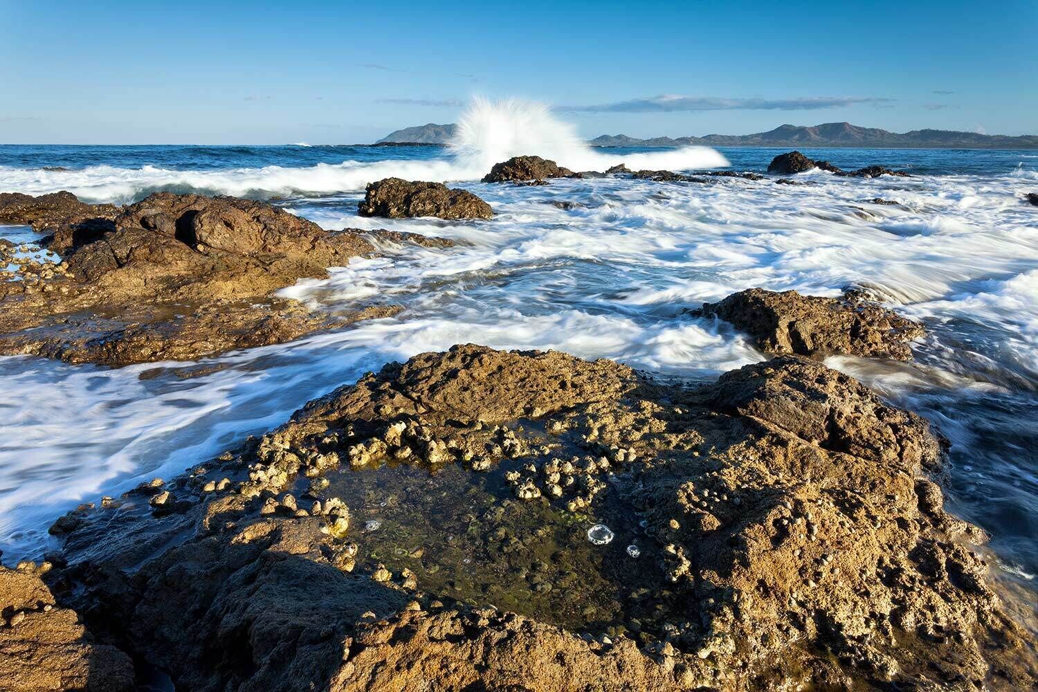 Un paysage côtier rocheux où les vagues s’écrasent contre les rochers.