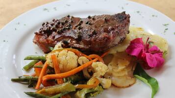 A plate of food with a steak, vegetables, and a flower garnish.
