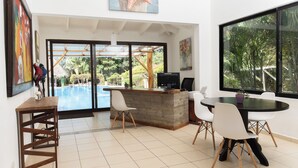 A modern dining area with a pool view, a bar, and a large window. - Seis Playas Hotel (Tamarindo)