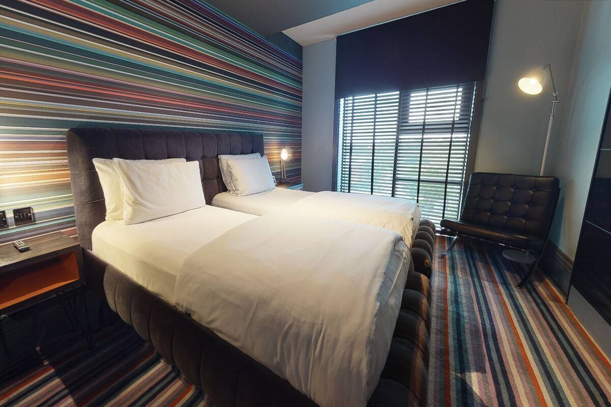 Une chambre d’hôtel avec un grand lit, une chaise et un mur à rayures.