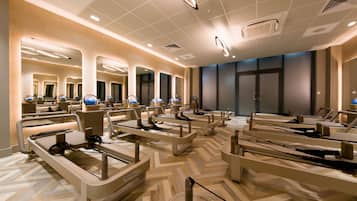 A modern hotel lobby with multiple massage chairs, a herringbone-patterned floor, and a large mirror wall.