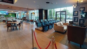 Un amplio vestíbulo de hotel con zona de bar, asientos y ventanas grandes que ofrecen vistas al exterior.
