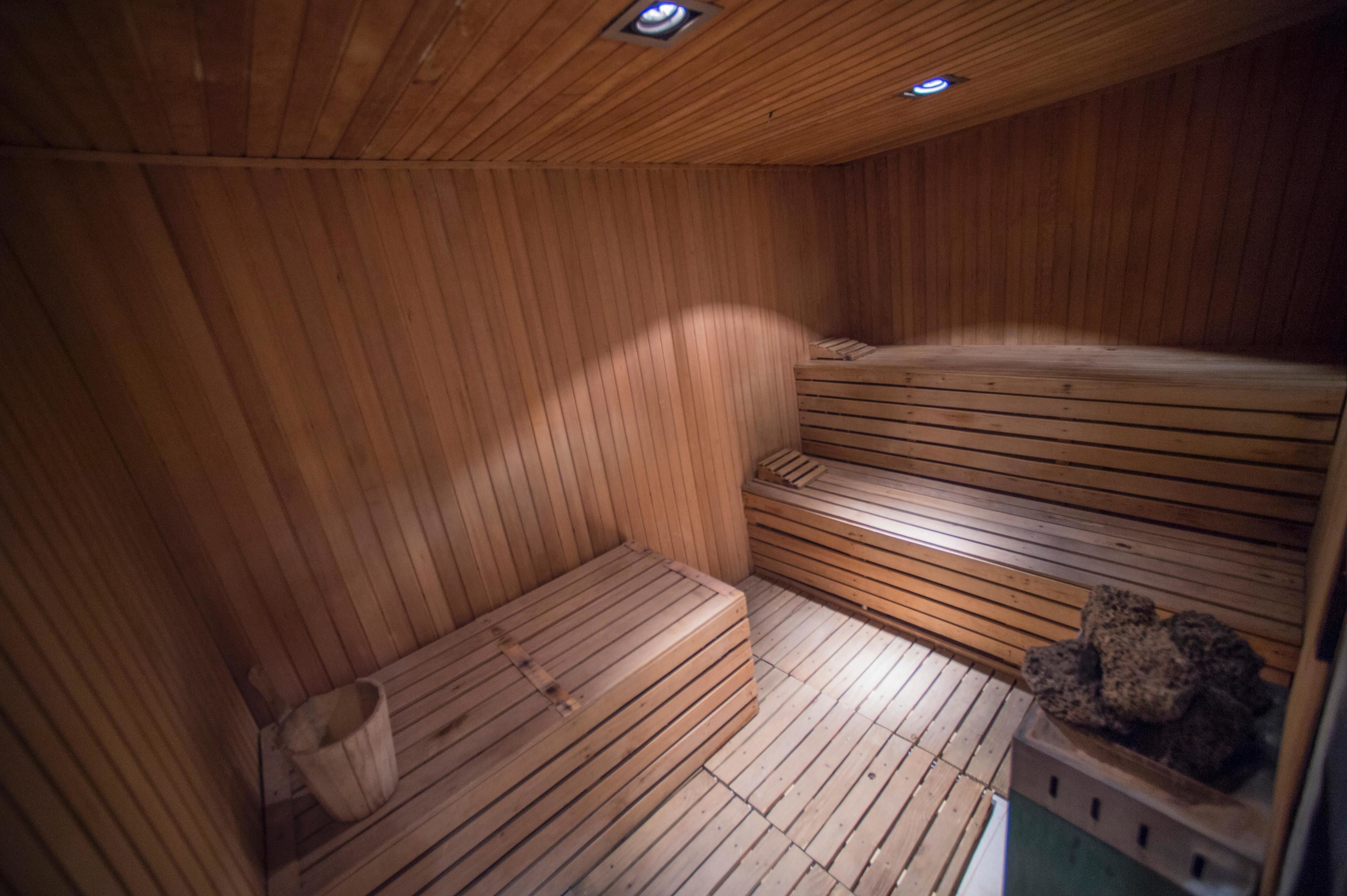 Uma sauna de madeira com bancos e uma bacia de pedra.