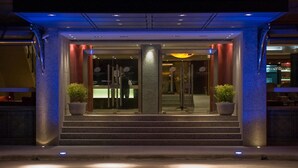 Ein Hotel mit Eingang, Glasdoor, Stufen und Blumentöpfen.