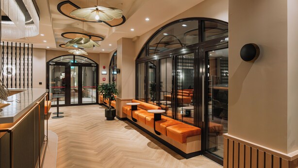 Un vestíbulo moderno con una recepción, un área de estar y puertas de cristal que dan a otras salas.