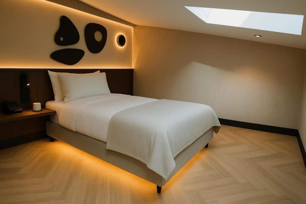 A modern bedroom with a skylight, a bed with white bedding, and a wooden floor.