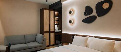 A modern hotel room with a large bed, a sofa, a built-in wardrobe, and a wall with circular light fixtures.