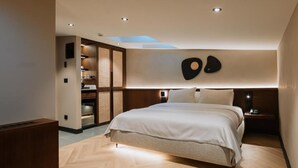 Un dormitorio moderno con una cama grande, estanterías empotradas y una lámpara de pared original.