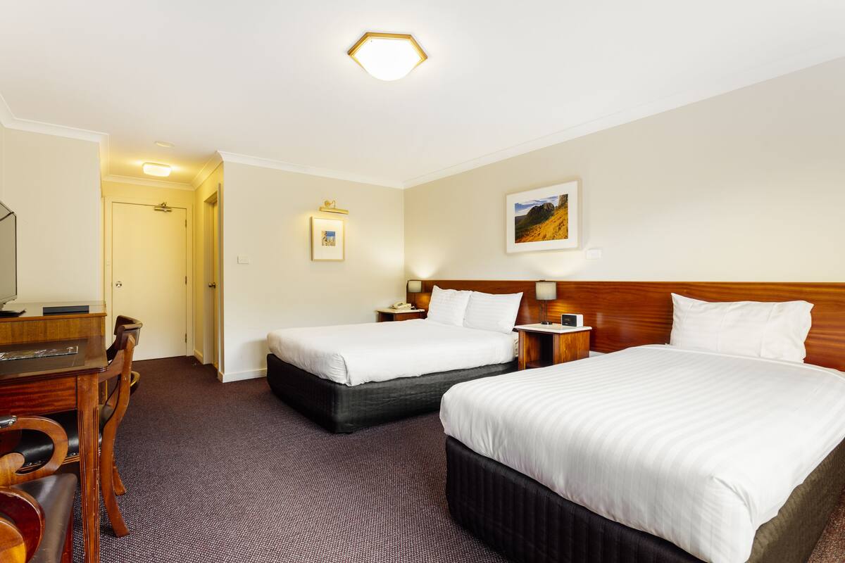Ein Hotelzimmer mit zwei Betten, einem Schreibtisch und einem Sessel.