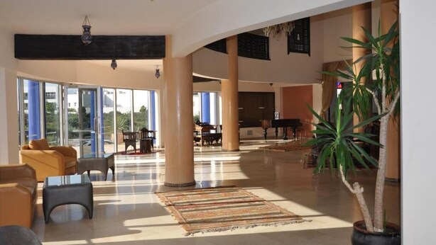 Un hall espacioso con ventanas amplias, un piano y una planta en maceta.