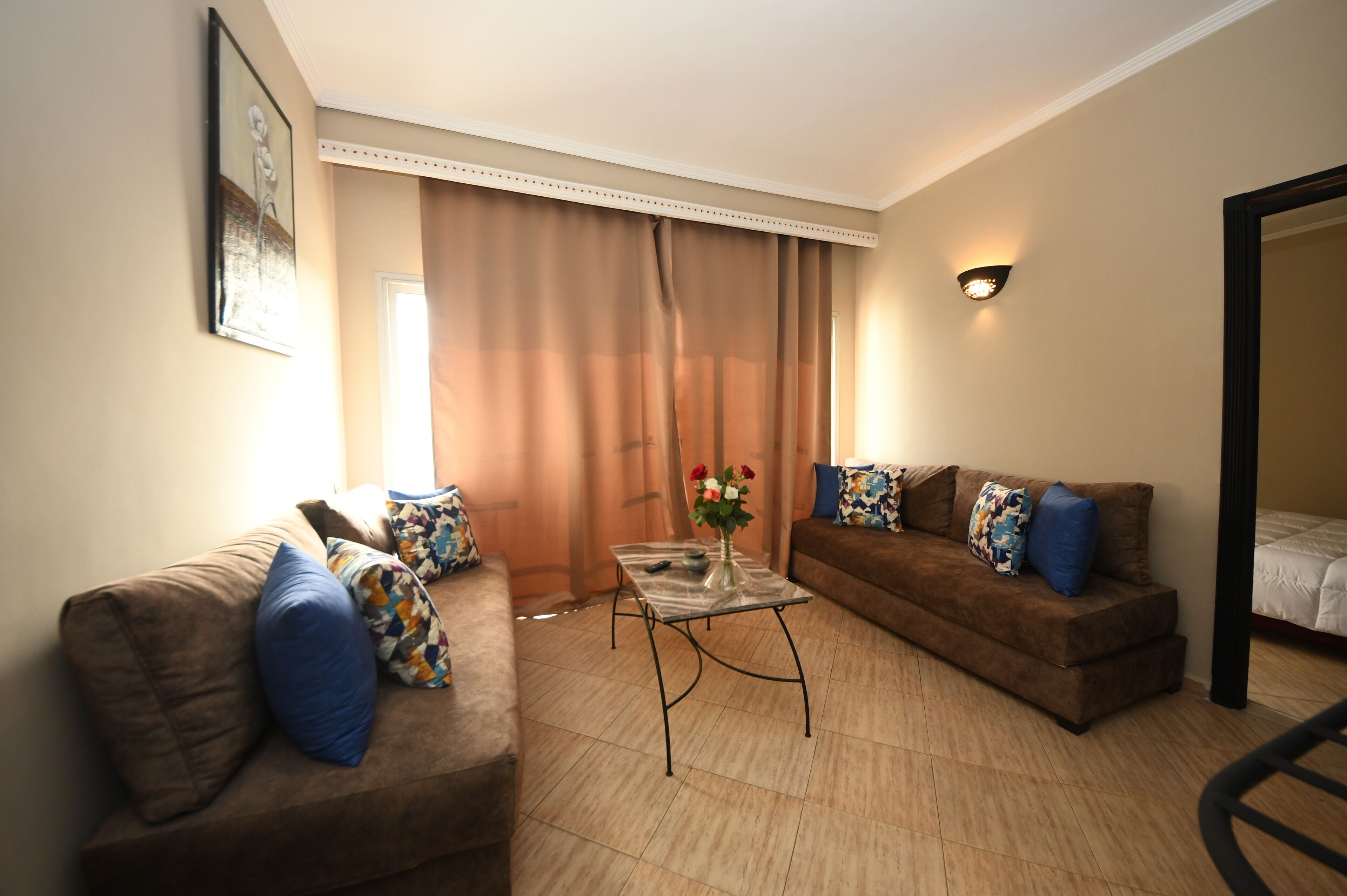 A living room with two brown sofas, a glass coffee table, and a vase with flowers.