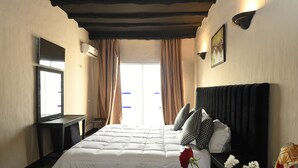 Habitación de hotel con una cama grande, televisor de pantalla plana, escritorio y ventana con cortinas.