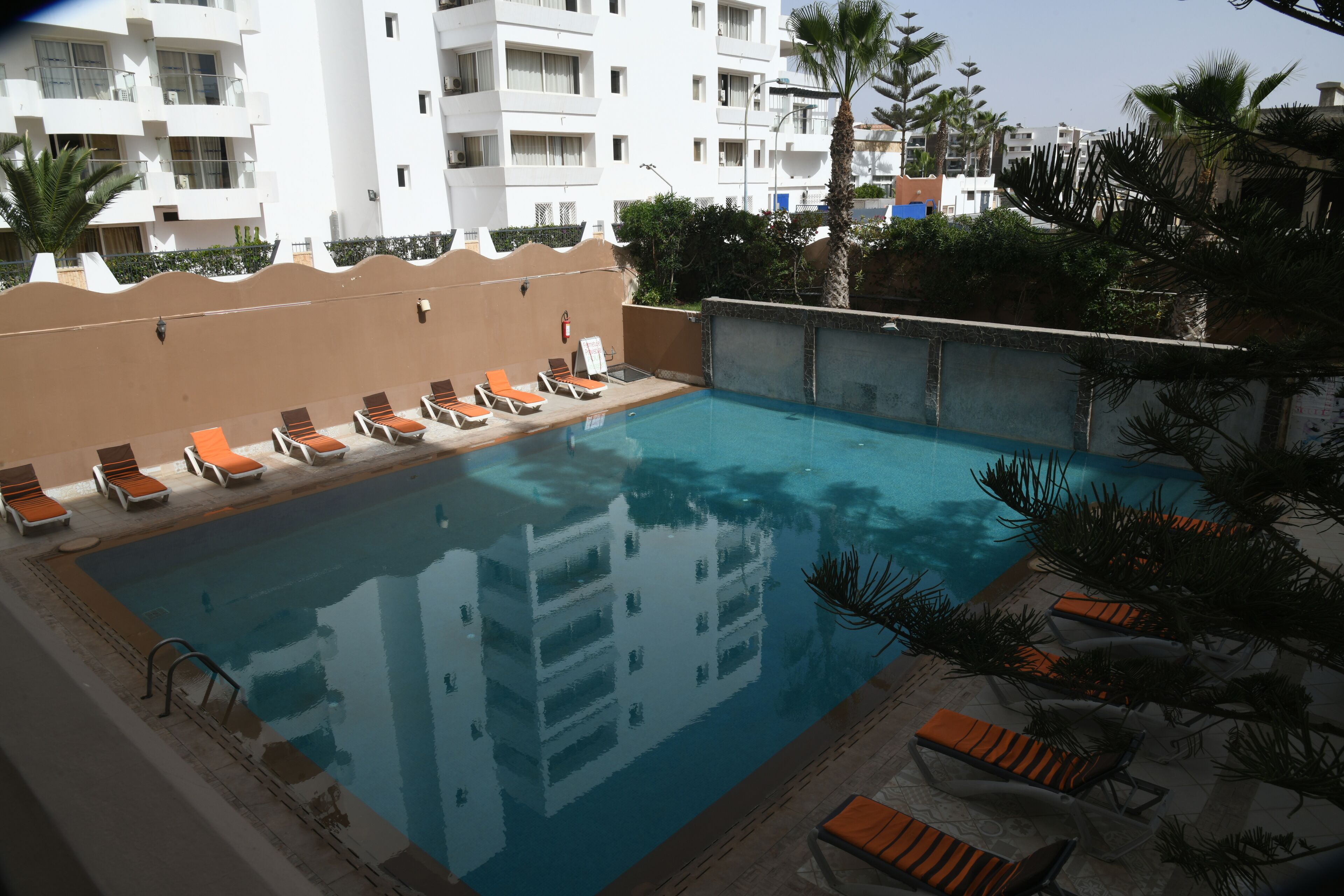 A swimming pool with lounge chairs and a building in the background.