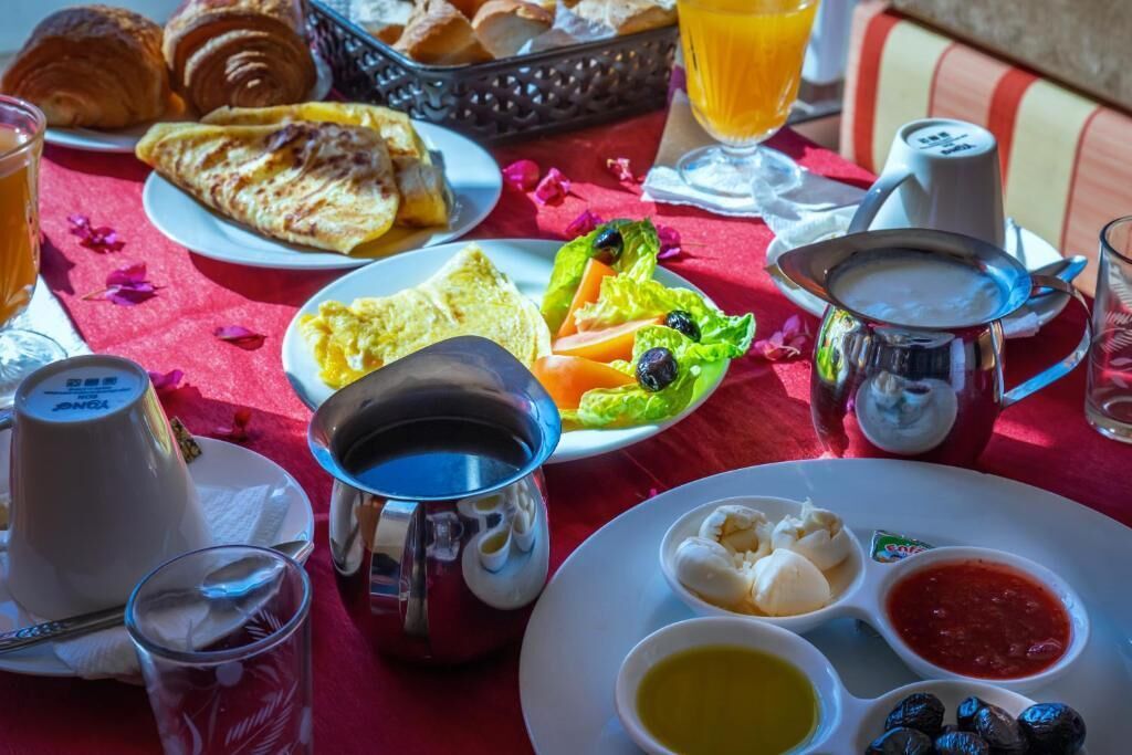 Una mesa de desayuno con cruasanes, tostadas, huevos y diferentes tipos de mermeladas y untables.