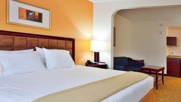 Een hotelkamer met een groot bed, een bedlampje, een bureau met telefoon en een stoel.