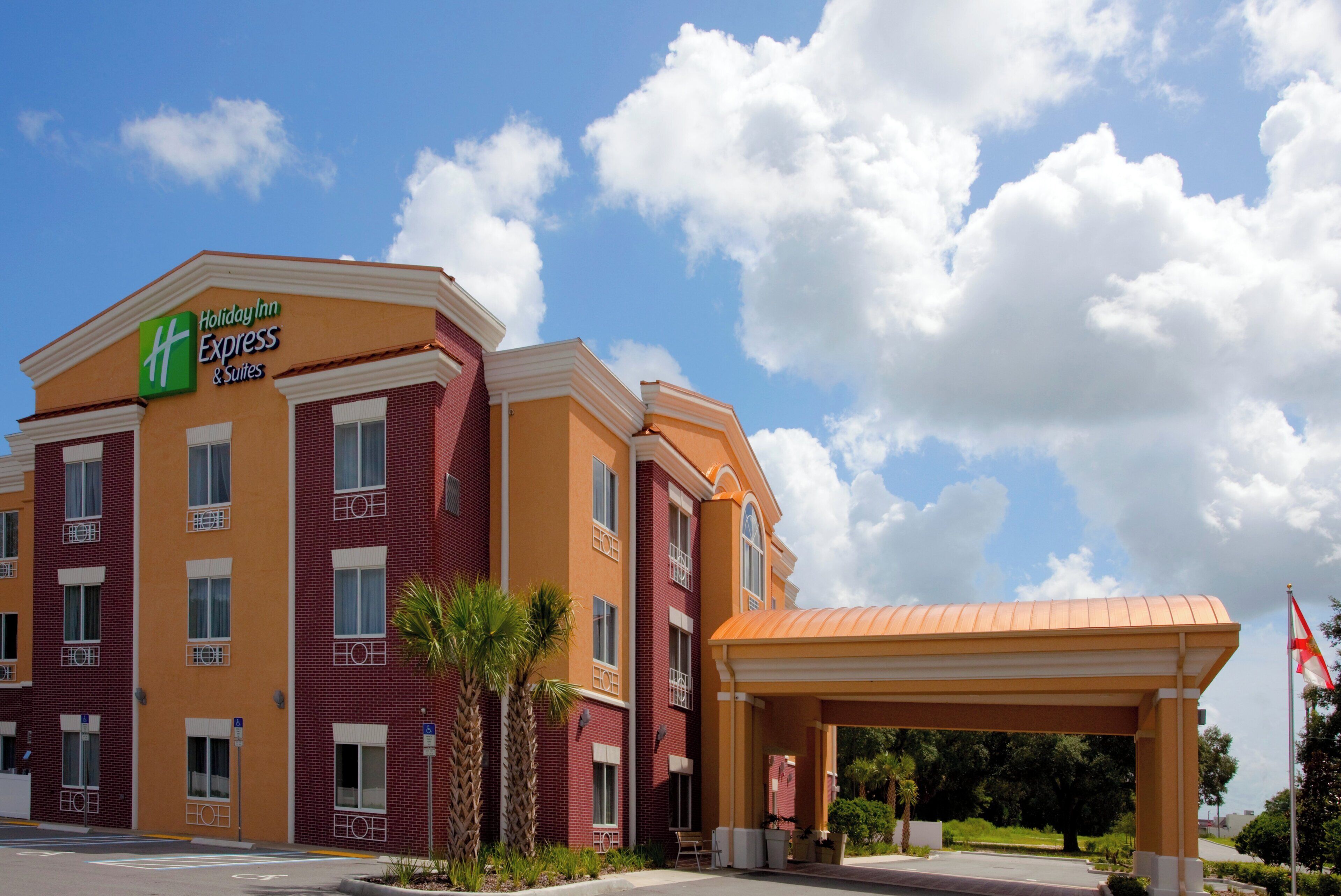 Ett Holiday Inn Express & Suites-hotell med en fasad av tegel, många fönster och en överbyggd entré.