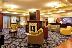 A hotel lobby with a fireplace, seating area, and a reception desk. - Holiday Inn Express Hotel & Suites Brooksville by IHG (Brooksville)