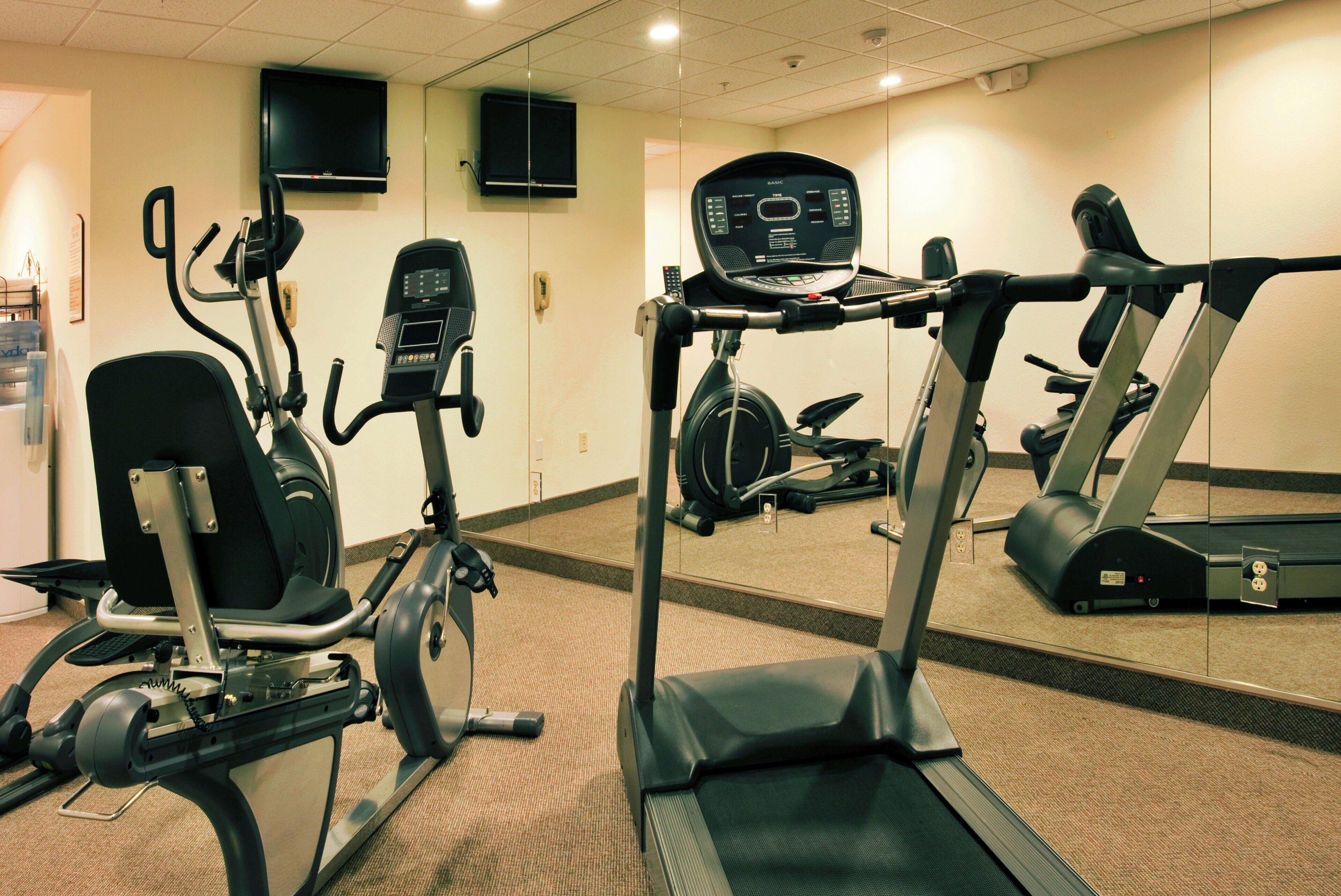 Centro de ginástica com equipamentos de exercício, incluindo esteira, bicicletas ergométricas e máquina elíptica.