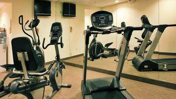 Centro de ginástica com equipamentos de exercício, incluindo esteira, bicicletas ergométricas e máquina elíptica.