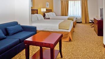 A hotel room with two beds, a sofa, a TV, and a desk.