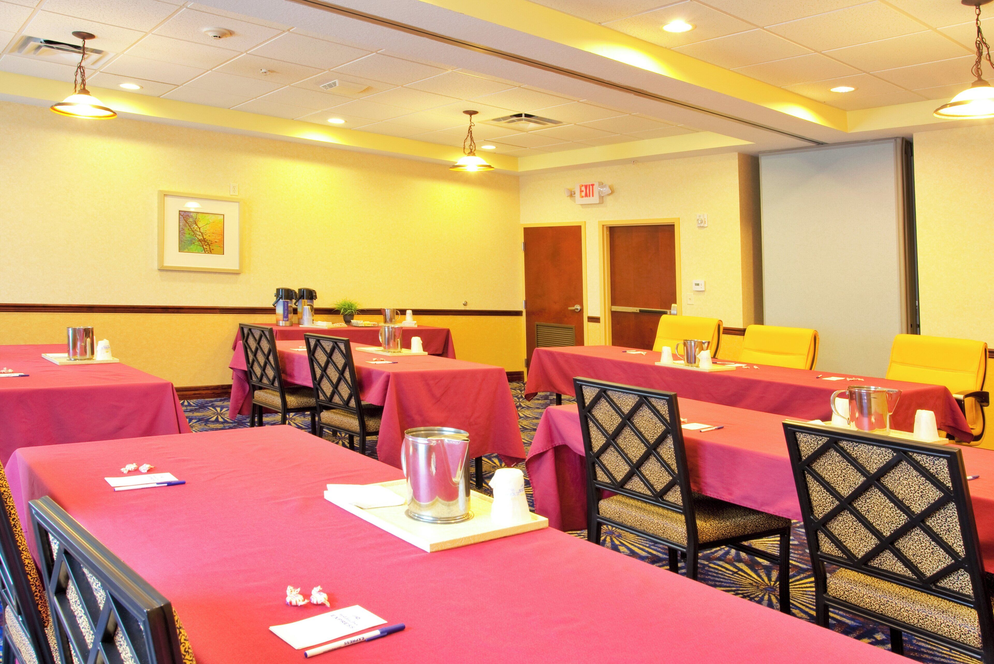 A conference room with tables set for meetings, equipped with nameplates, pens, and water pitchers.