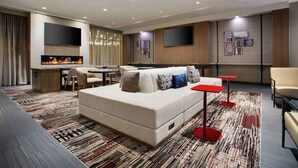 A modern hotel room with a sofa, a flat-screen TV, a fireplace, and a dining area. - DoubleTree by Hilton Chicago Midway Airport (Chicago)