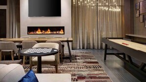 A modern living room with a fireplace, a flat-screen TV, a pool table, and a chess table. - DoubleTree by Hilton Chicago Midway Airport (Chicago)