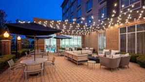 An outdoor patio area with seating, tables, and string lights. - DoubleTree by Hilton Chicago Midway Airport (Chicago)