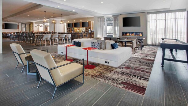 A modern hotel lobby with a seating area, a bar, and a kitchen. - DoubleTree by Hilton Chicago Midway Airport (Chicago)