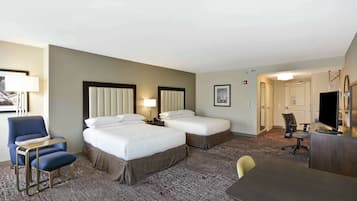 Habitación de hotel con dos camas, un escritorio, una silla y un televisor.